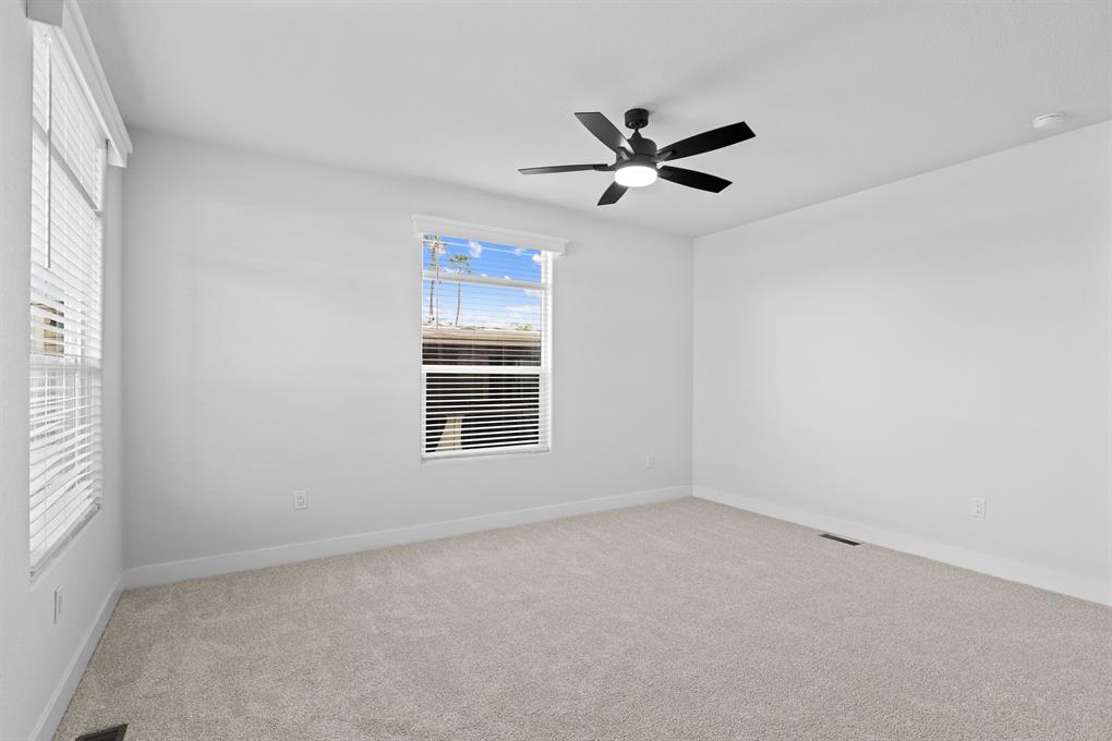 Spacious primary bedroom with ceiling fan for year-round comfort
