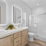 Spacious primary bathroom with double sinks and lighted mirrors