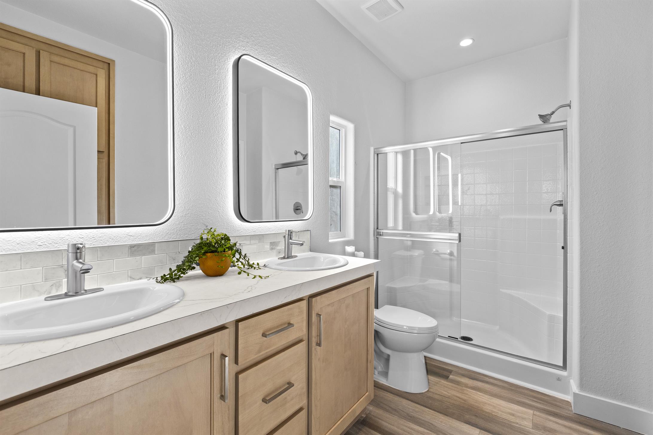 Spacious primary bathroom with double sinks and lighted mirrors